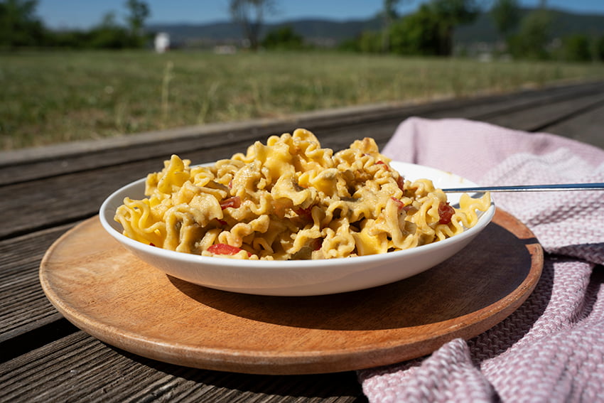 Mafaldine mit Avocadosauce in einem tiefen Teller mit Tomatenstücken als Topping angerichtet
