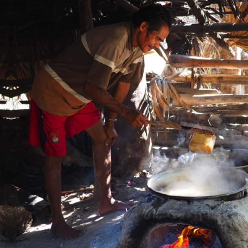 Mann der auf traditionelle Weise über einem Feuer Kokosblütenzucker auskocht